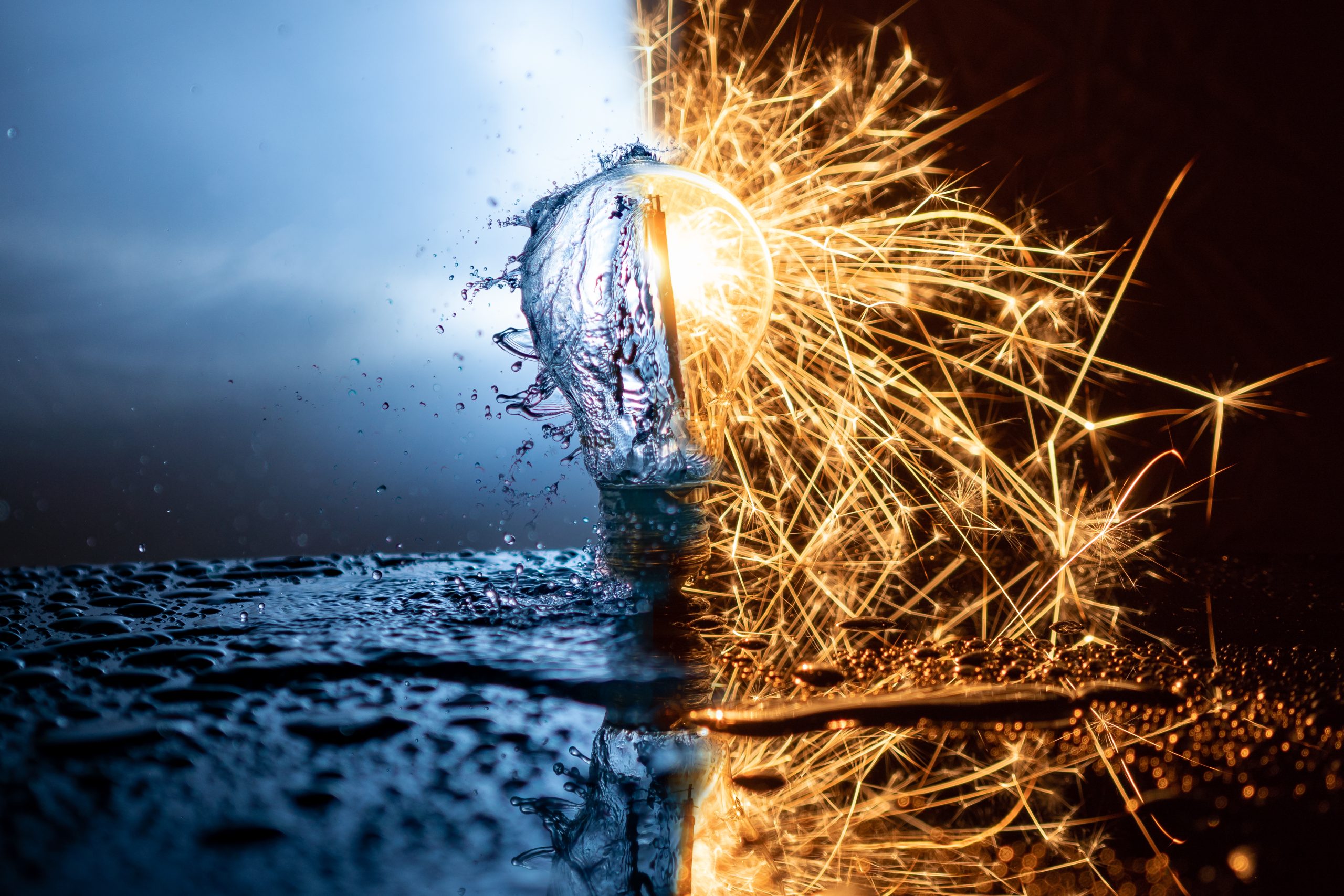 A light bulb with watersplashes on one side and sparks on the other side. reflections on the floor.